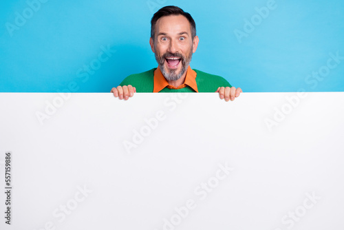 Photo portrait of mature attractive male hiding behind white blank white wall dressed stylish green look isolated on blue color background