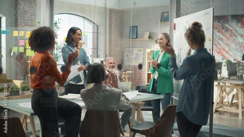 Woman Finishing a Presentation in a Meeting Room at Office With Multiethnic Team. She is Presenting Company Growth Data and Marketing Strategy. Colleagues Clapping, Cheering, Celebrating her Success.