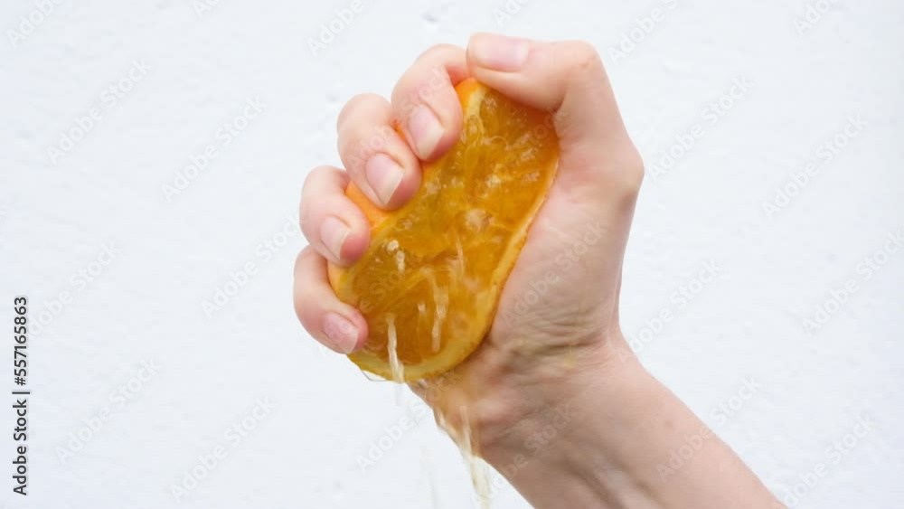 Hand squeezes half of an orange and orange juice flows isolated on white background. Slow motion full HD video of orange fruite in hand. Hand squeezes half of an orange and orange juice flows isolated on white background. Slow motion full HD video of orange fruite in hand.