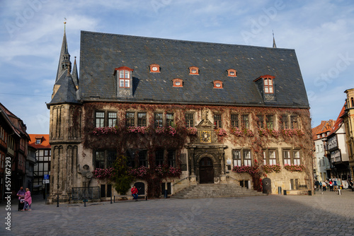 Quedlinburg, Saxony-Anhalt, Germany, 28 October 2022: Historic gothic townhall or Rathaus with Roland statue in Market Square, vintage colored timber frame houses in medieval town at sunny autumn day photo