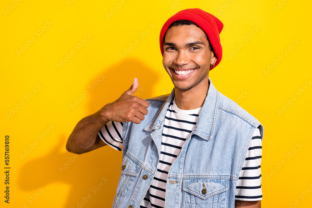 Photo of positive man toothy smile wear trendy outfit arm thumb up quality nice service piercing isolated on yellow color background