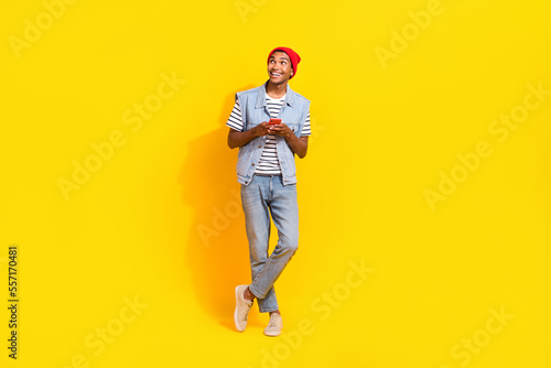 Photo of dreamy charming guy dressed denim clothes empty space chatting instagram twitter isolated yellow color background © deagreez