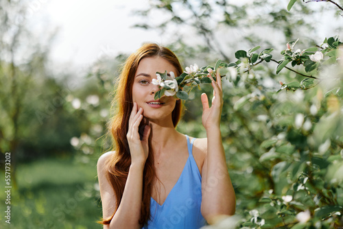 Woman portrait beautifully smiling with teeth spring happiness in nature against a green tree hand touch tenderness, safety from allergies and insects