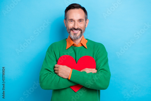 Photo of mature age experienced boyfriend man wear green jumper hug big red paper love symbol enjoy valentine day isolated on blue color background © deagreez