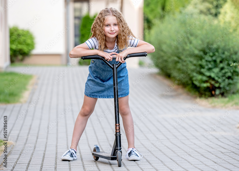 Naklejka premium Little girl rides a kick scooter