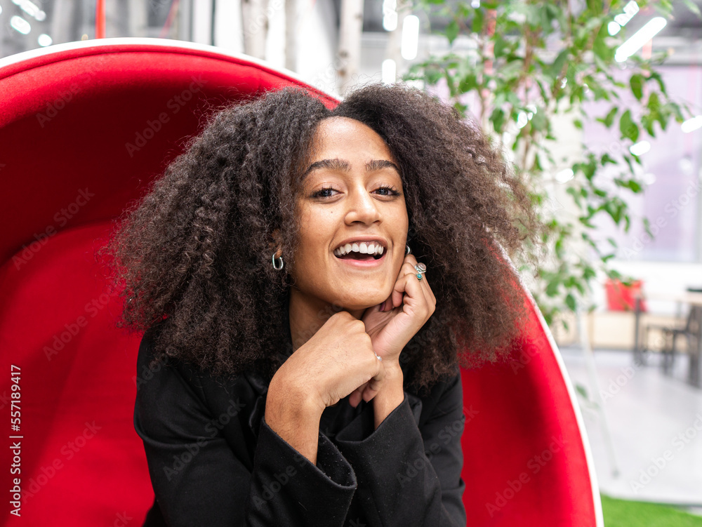 Smiling black woman sitting on swing chair in office Stock Photo ...