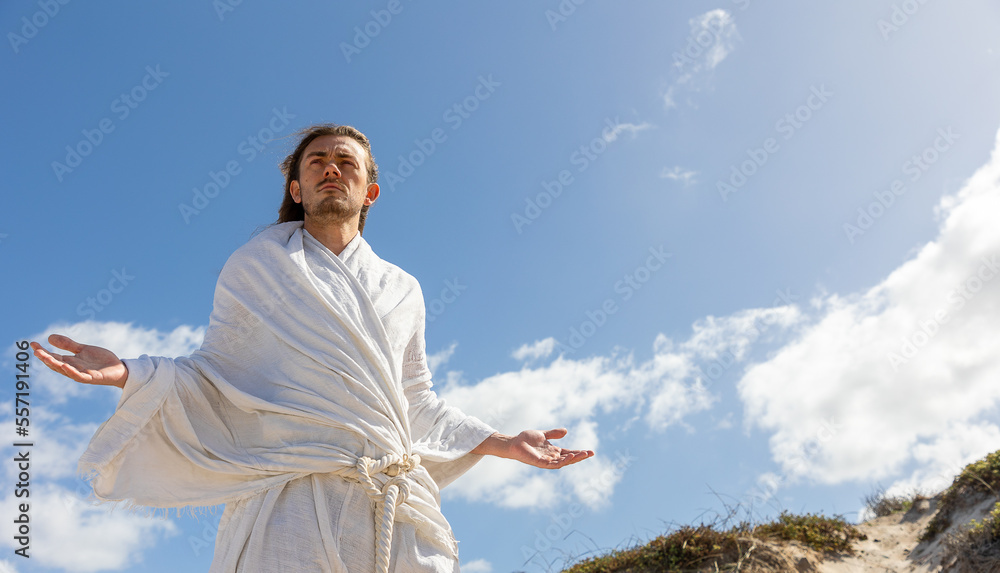 Man praying with open arms, white robe, long hair and beard.