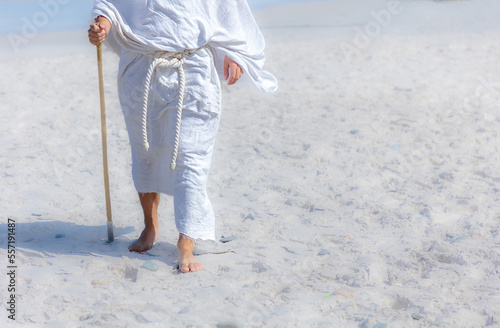 close up of a Biblical man in a white robe and staff walking in desert photo