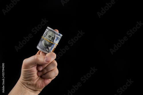 Rolled up bundle of 100 dollar bills on the finger of a man's hand