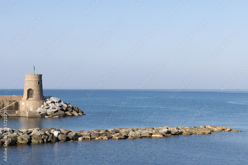 Old small lighthouse and stone wave breakers of Recco on a sunny summer day. Recco is a comune in the Metropolitan City of Genoa, region of Liguria, Italy.