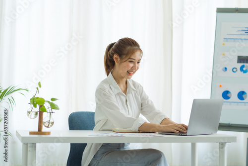 Attractive asia employees in successful modern office university education Financial graphs on her workstation. Young asian freelance employee online marketing ecommerce telemarketing concept report