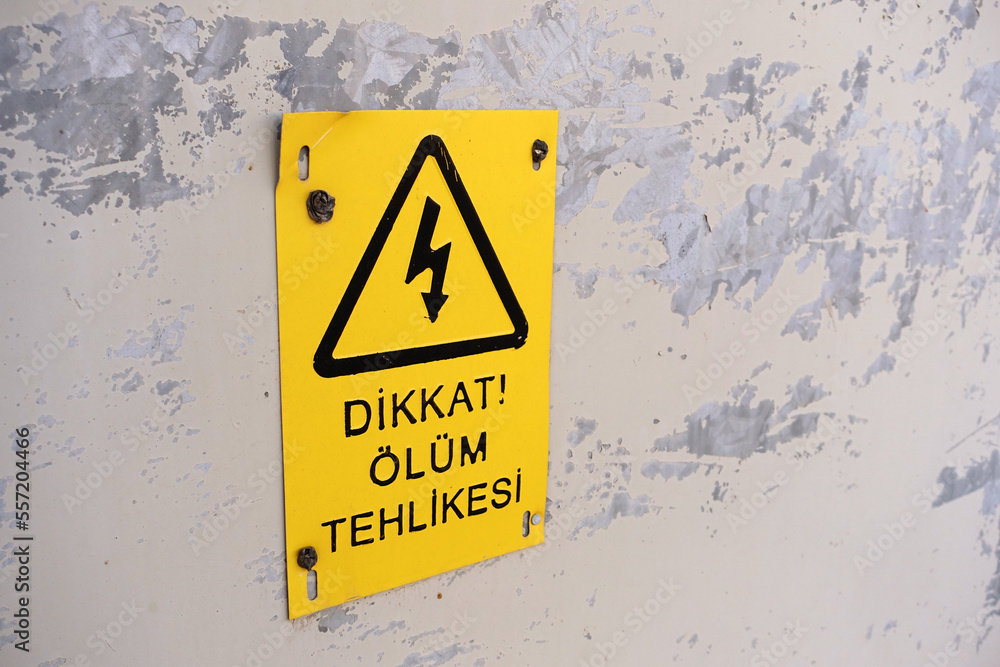 A sign board with a black font on the yellow plate with a death hazard warning sign, a Turkish death hazard warning sign, A sign board with a black font on the yellow plate with a death hazard warning sign, a Turkish death hazard warning sign,