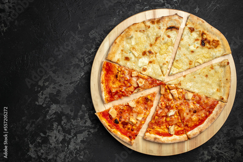 Tasty hawaiian pizza with chicken and pineapple pizza Four Cheeses on wooden cutting board on a dark background. food delivery, place for text, top view