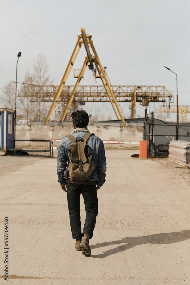 Back view shot of unrecognizable man walking along industrial area Back view shot of unrecognizable man walking along industrial area