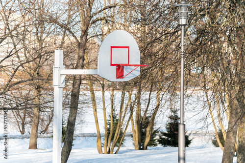 Basketball backboard with a ring in the park in winter on a background of snow. Basketball in winter.
