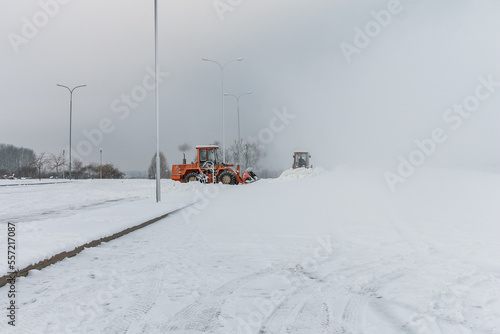 Obraz na płótnie Bulldozers remove snow with an iron bucket after a blizzard. Cleaning snowdrifts with a bulldozer. Cleaning the city after a blizzard. w salonie