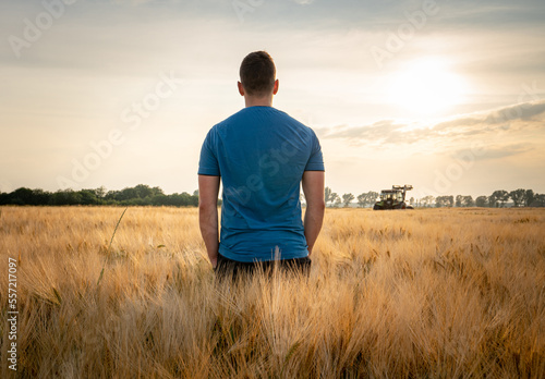 Was bringt die Zukunft: Junger Landwirt steht mit den Rücken zur Kamera im Gegenlicht, in einem reifen Getreidefeld. © Countrypixel