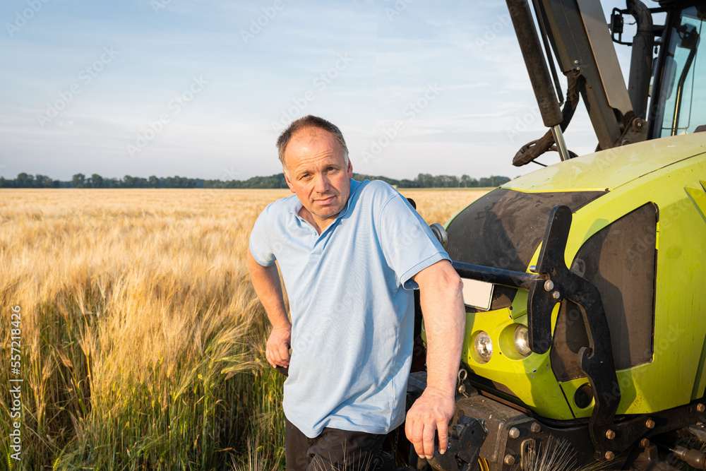 Einfach mal eine Pause machen, Landwirt steht am Trecker im Getreidefeld.