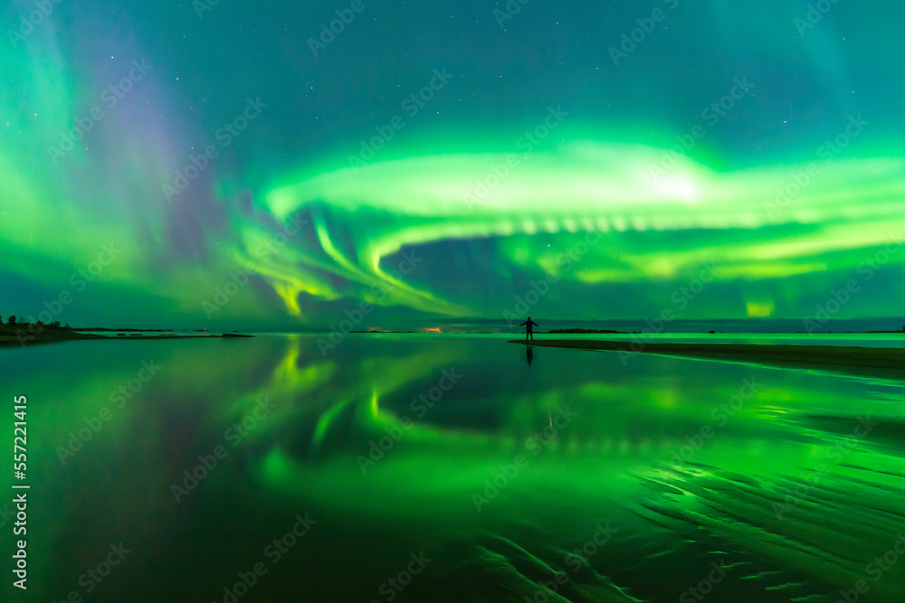 Northern lights reflected in water. Person standing on the bech. Storsand, Jakobstad/Pietarsaari Finland.