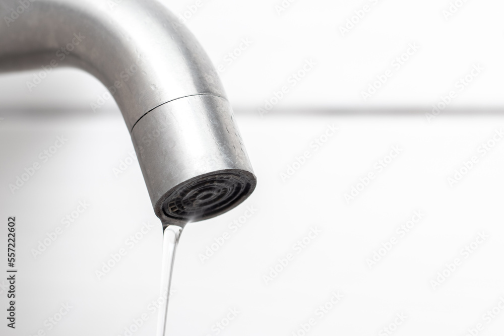 Water flows from the faucet in the bathroom. Water faucet close-up. Saving water. The faucet needs repair Water flows from the faucet in the bathroom. Water faucet close-up. Saving water. The faucet needs repair