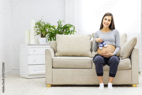 Photo of pregnant woman with naked stomach and child clothes.