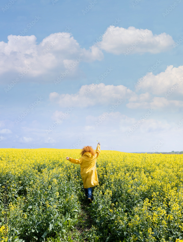 Fototapeta premium A woman running in a yellow field on a warm spring day