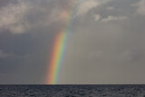 A bright rainbow appears over the South Pacific Ocean during the monsoon season.