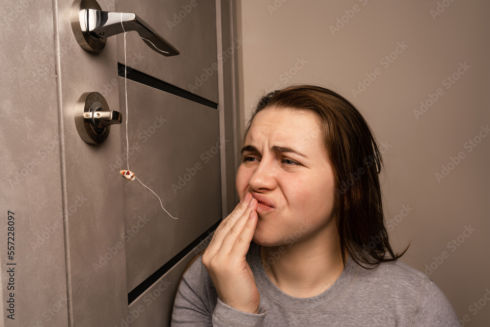 The girl is holding a thread to pull out a tooth. Extraction of a tooth