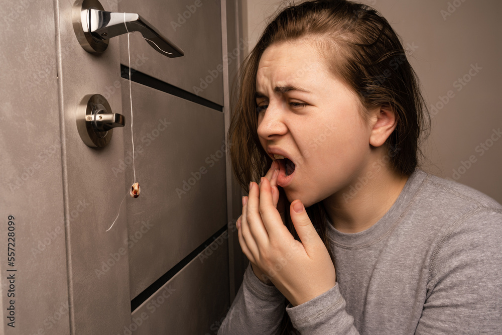The girl is holding a thread to pull out a tooth. Extraction of a tooth ...