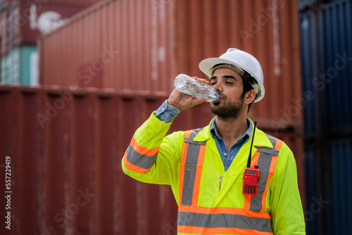 Workers or engineers drink water to quench their thirst at the container yard. Working on hot days. The concept of transportation in a container warehouse. photo