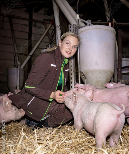 Knieend im eingestreuten Schweinestall, hat die junge Landwirtin direkten Kontakt zu ihren Schweinen. photo