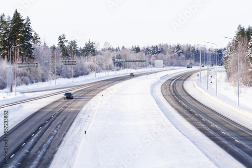 Winter highway. Asphalt road through a snowy forest. Car driving on a heavy winter road. Snowy and frozen road in winter landscape.