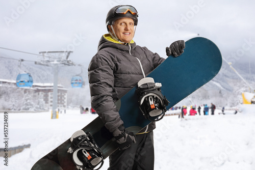 Mature man with snowboard posing at a ski resort
