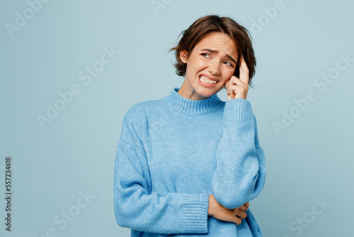 Young mistaken sad unhappy caucasian woman wear knitted sweater look aside on workspace area prop up chin isolated on plain pastel light blue cyan background studio portrait. People lifestyle concept. photo