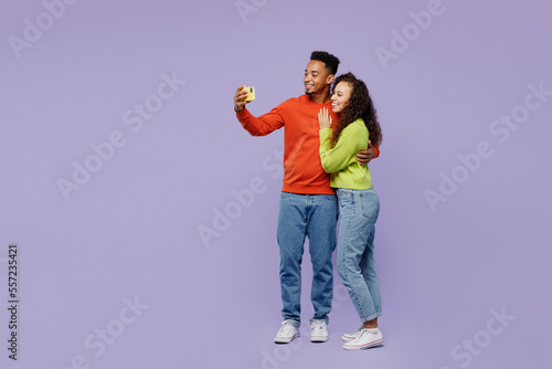 Full body side view young couple two friends family man woman of African American ethnicity wear casual clothes doing selfie shot mobile cell phone together isolated on plain light purple background.