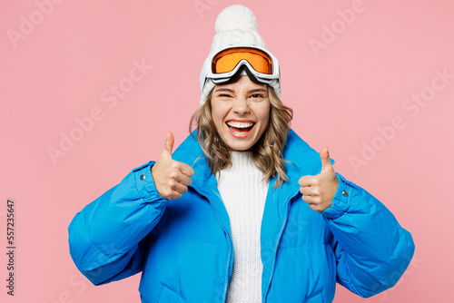 Snowboarder woman wear blue suit goggles mask hat ski padded jacket spend extreme weekend showing thumb up like gesture isolated on plain pastel pink background. Winter sport hobby trip relax concept.