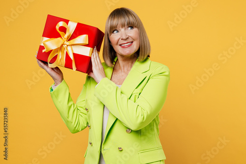 Canvas Print Elderly happy woman 50s years old wearing green jacket white t-shirt hold gift certificate coupon voucher card for store isolated on plain yellow background studio portrait