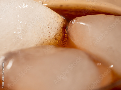 Cola with ice in a glass. Carbonated refreshing drink with ice. Cola bubbles.