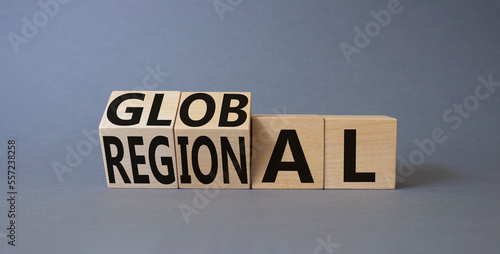 Global and Regional symbol. Businessman hand points at turned wooden cubes with words Regional and Global. Beautiful grey background. Business and Global and Regional concept. Copy space