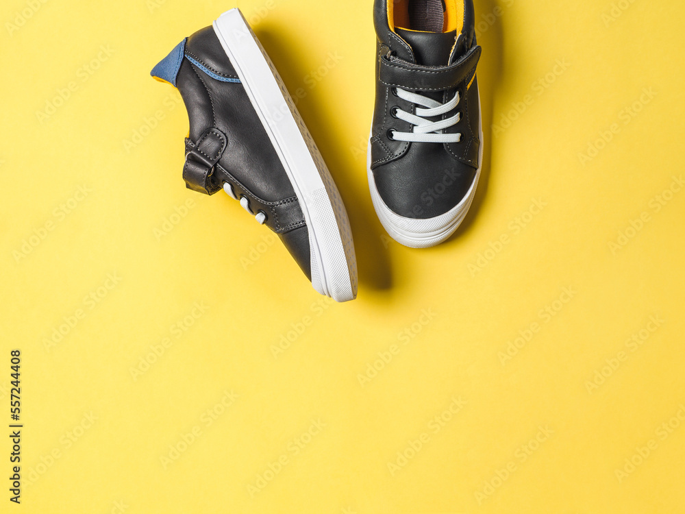 pair of new kids or adult sneakers on yellow background top view
