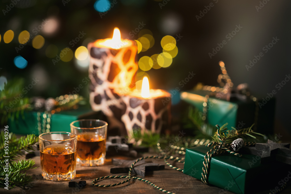 Two shot glasses of whiskey or bourbon with Holiday decoration on wooden background. New Year, Christmas and winter holidays whiskey mood concept Two shot glasses of whiskey or bourbon with Holiday decoration on wooden background. New Year, Christmas and winter holidays whiskey mood concept