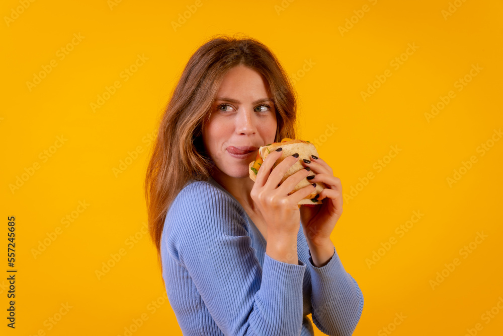 Portrait of cheerful woman eating a sandwich on a yellow background, healthy and vegetarian food Portrait of cheerful woman eating a sandwich on a yellow background, healthy and vegetarian food