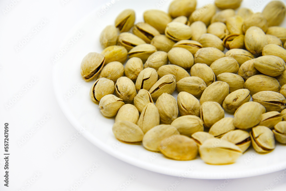 Delicious pistachios on a white plate. Pistachios in a pile on a white plate. Appetizer for beer. Delicious pistachios on a white plate. Pistachios in a pile on a white plate. Appetizer for beer.