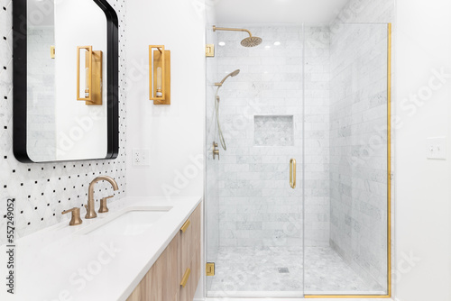 Canvastavla A bathroom with a wood cabinet, tiled backsplash, gold faucets and lights, and a marble tiled shower