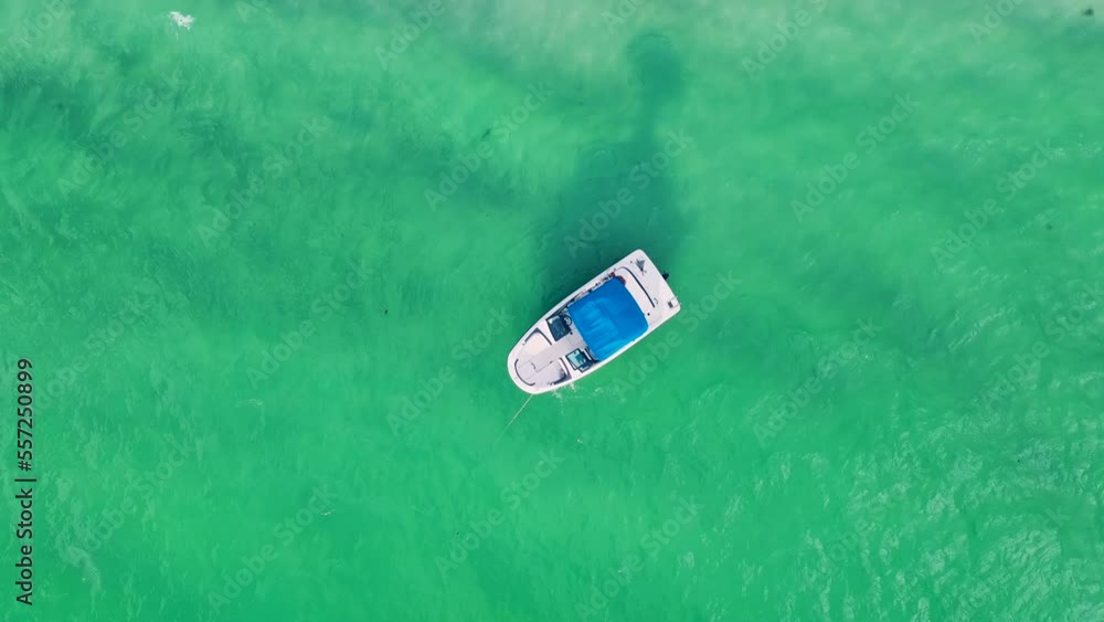Aerial view of small white motorboat floating on sea waves with ripple surface near sandy beach. Motor boat recreation on ocean surface Aerial view of small white motorboat floating on sea waves with ripple surface near sandy beach. Motor boat recreation on ocean surface