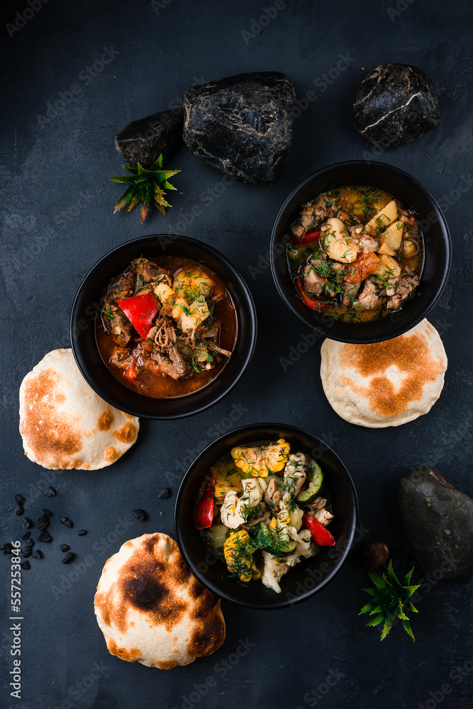 Set of chicken, pork and beef stew with vegetables in bowls.