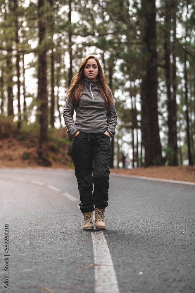 caucasian girl walking along a road in the middle of the forest caucasian girl walking along a road in the middle of the forest