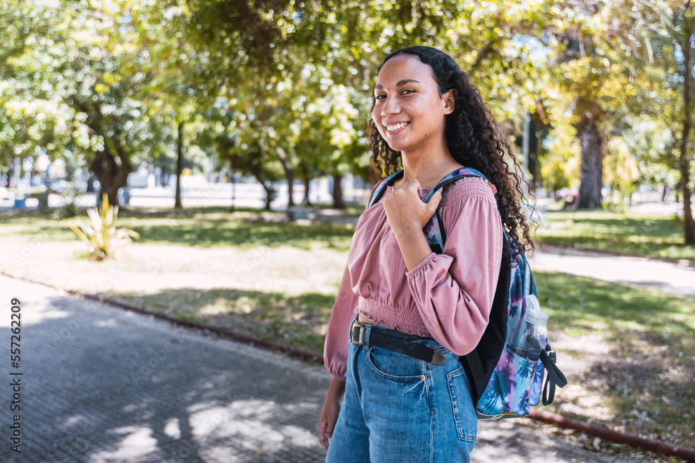 Happy young latin student woman standing in the park. Determination. Centennial generation Happy young latin student woman standing in the park. Determination. Centennial generation