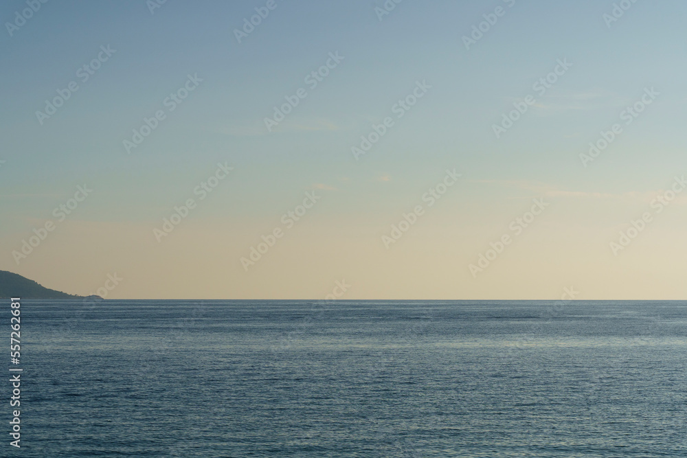 Clean seascape background with blue light evening sky and horizon. Summer evening sea after sunset or before sunrise. Tranquility, relaxation, silence concept.
