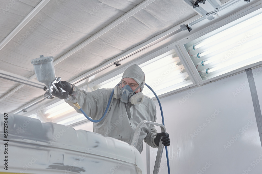 Horizontal shot of man wearing work clothes and respirator painting vehicle Horizontal shot of man wearing work clothes and respirator painting vehicle